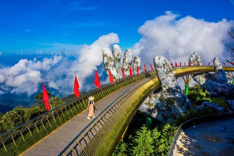 Cầu Vàng tại Bà Nà Hills, Đà Nẵng là điểm check-in làm mưa làm gió trên các mạng xã hội vài năm trở lại. Cầu Vàng được khánh thành vào tháng 6.2018, nằm trong khuôn viên khu du lịch Sun World Ba Na Hills. Giống như tên gọi của mình, Cầu Vàng mang màu vàng lấp lánh và nổi bật giữa thiên nhiên xanh mát. Hình dáng mềm mại như một dải lụa vàng được nâng đỡ bởi đôi bàn tay đá khổng lồ, tạo nên một lối đi giữa những tầng không đầy huyền ảo trong khung cảnh mờ sương của núi Bà Nà. Ảnh: Vietravel