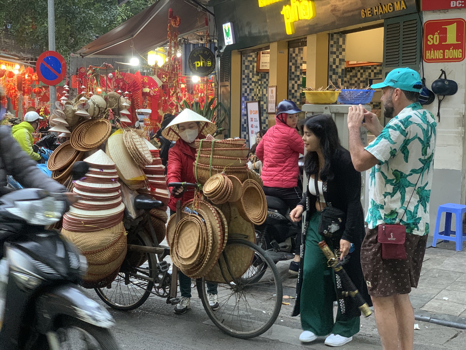 Khách nước ngoài chọn mua quà lưu niệm trên phố Hàng Mã, Hà Nội. Ảnh: Ý Yên