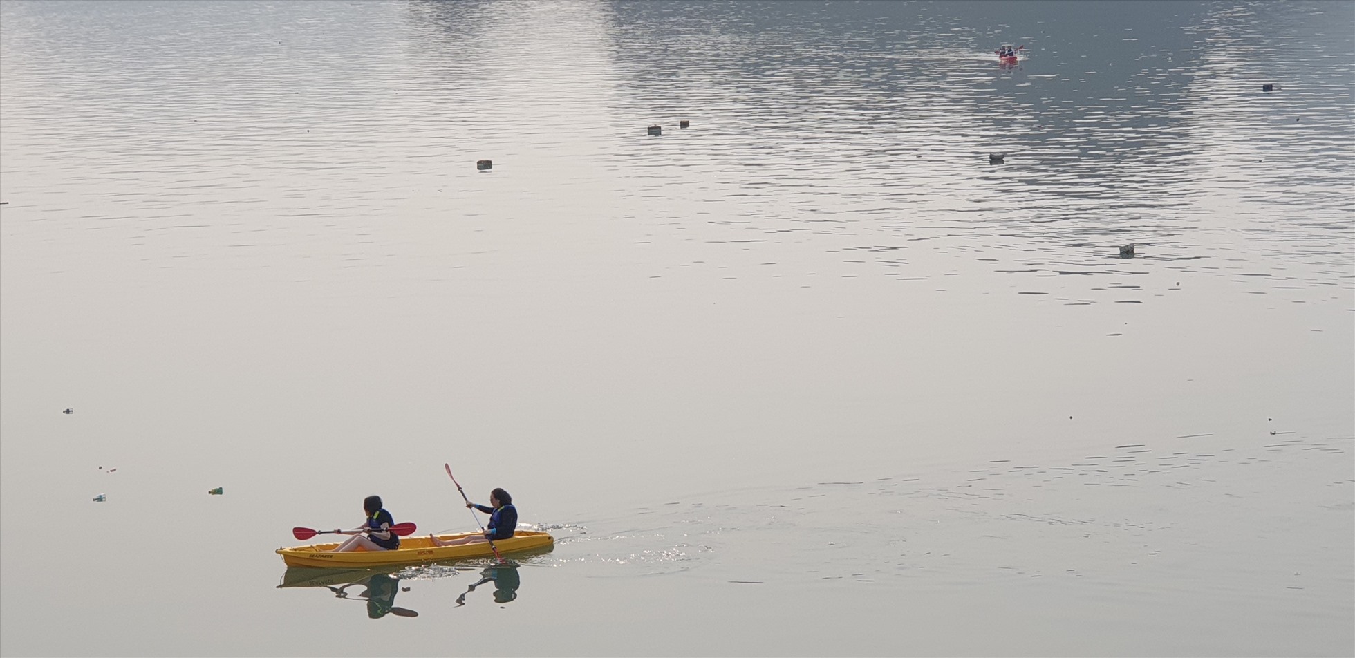 Du khách chèo thuyền kayak trên vịnh Lan Hạ, xung quanh tràn ngập phao xốp. Ảnh: Nguyễn Hùng