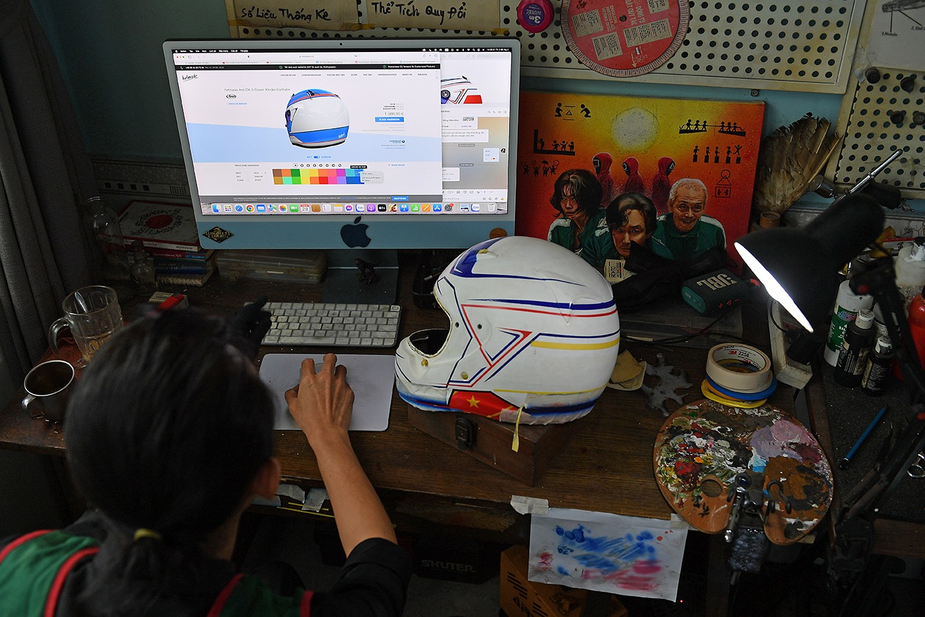 Thạch đang thiết kế mẫu vẽ trên máy tính cho một cái mũ. ảnh: Việt Văn.