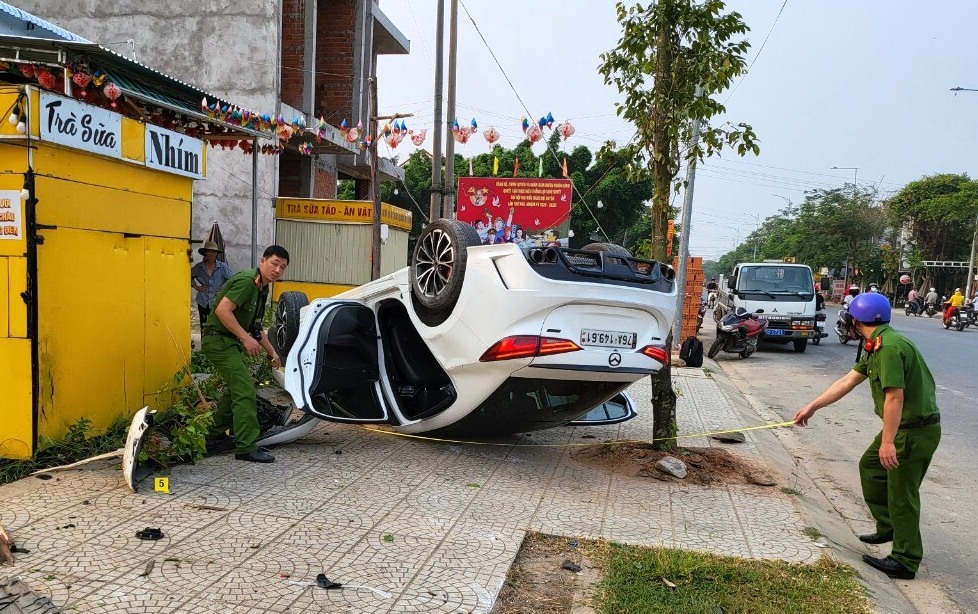 Chiếc xe ô tô phóng lên vỉa hè đâm ngã một cây xanh rồi lật ngửa. Ảnh: Công an huyện Nghĩa Hành.