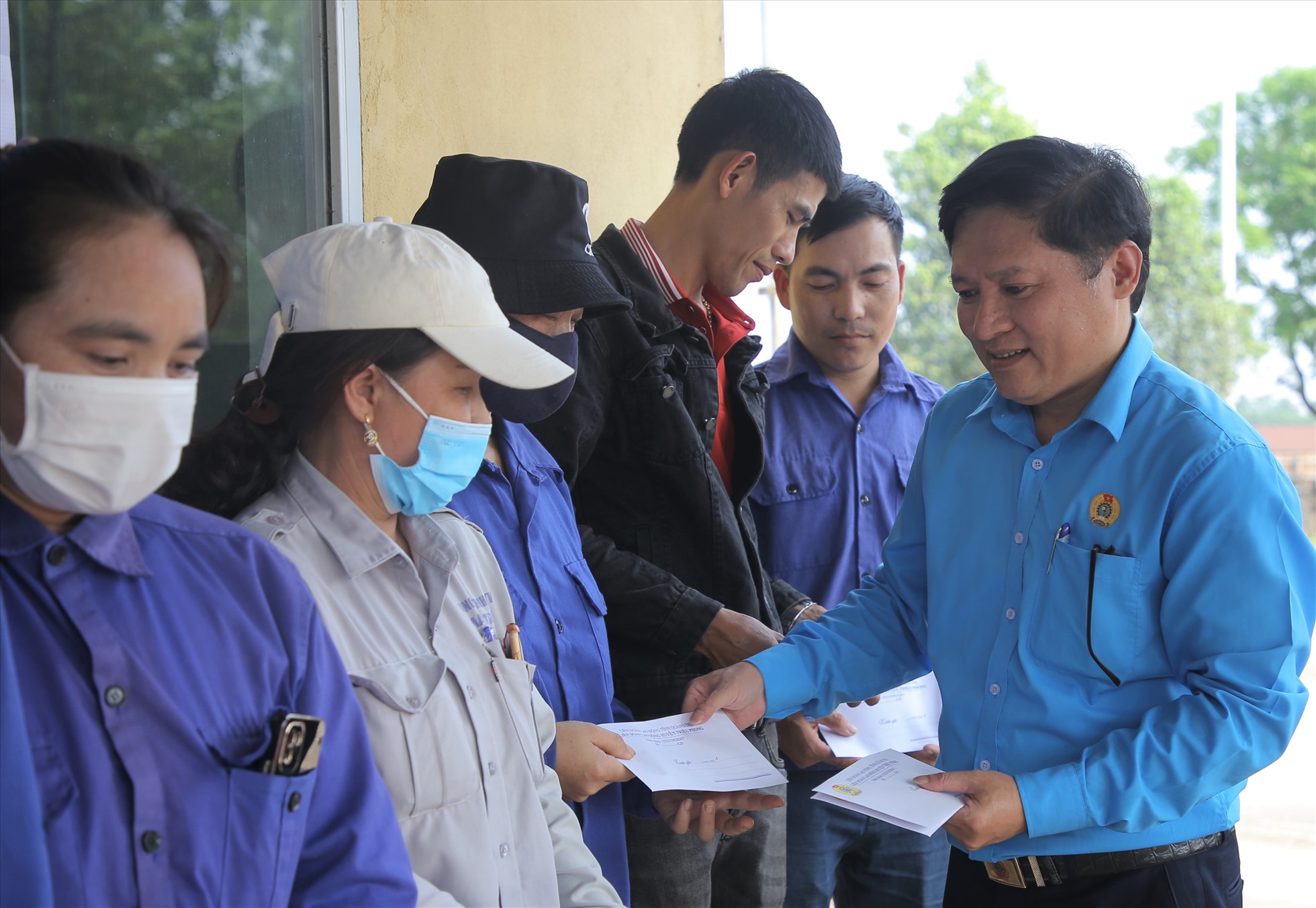 Ông Nguyễn Duy Ninh - Chủ tịch LĐLĐ huyện Triệu Phong trao tiền hỗ trợ cho công nhân. Ảnh: Hưng Thơ.