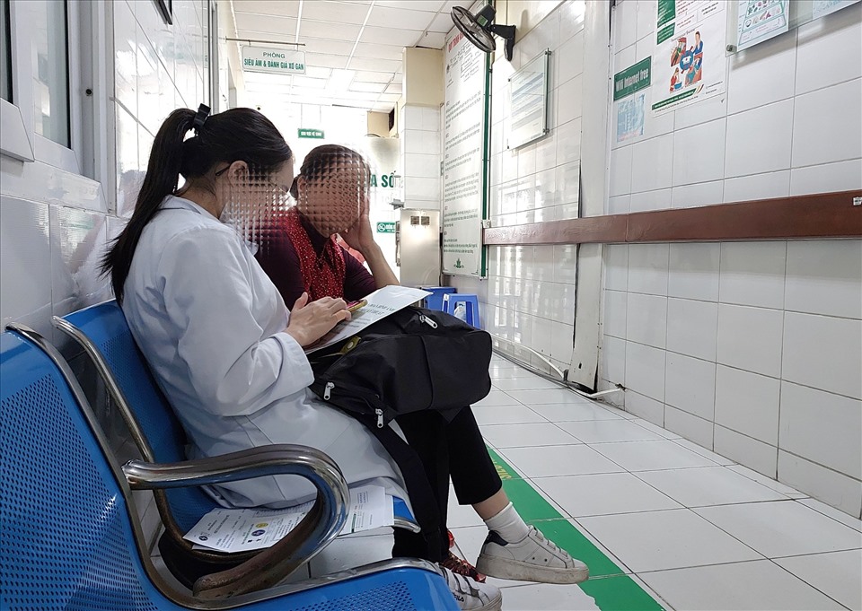 Một người dân đến khám bệnh tại Bệnh viện Nhiệt đới Trung ương không đeo khẩu trang trong lúc nói chuyện với sinh viên thực tập.