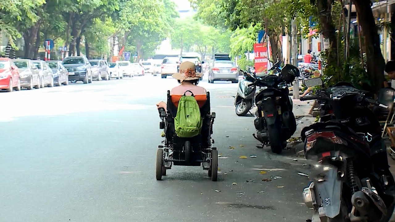 Không thể đi trên lối đi dành riêng, người khuyết tật phải đi xuống lòng đường. Ảnh: Minh Hạnh