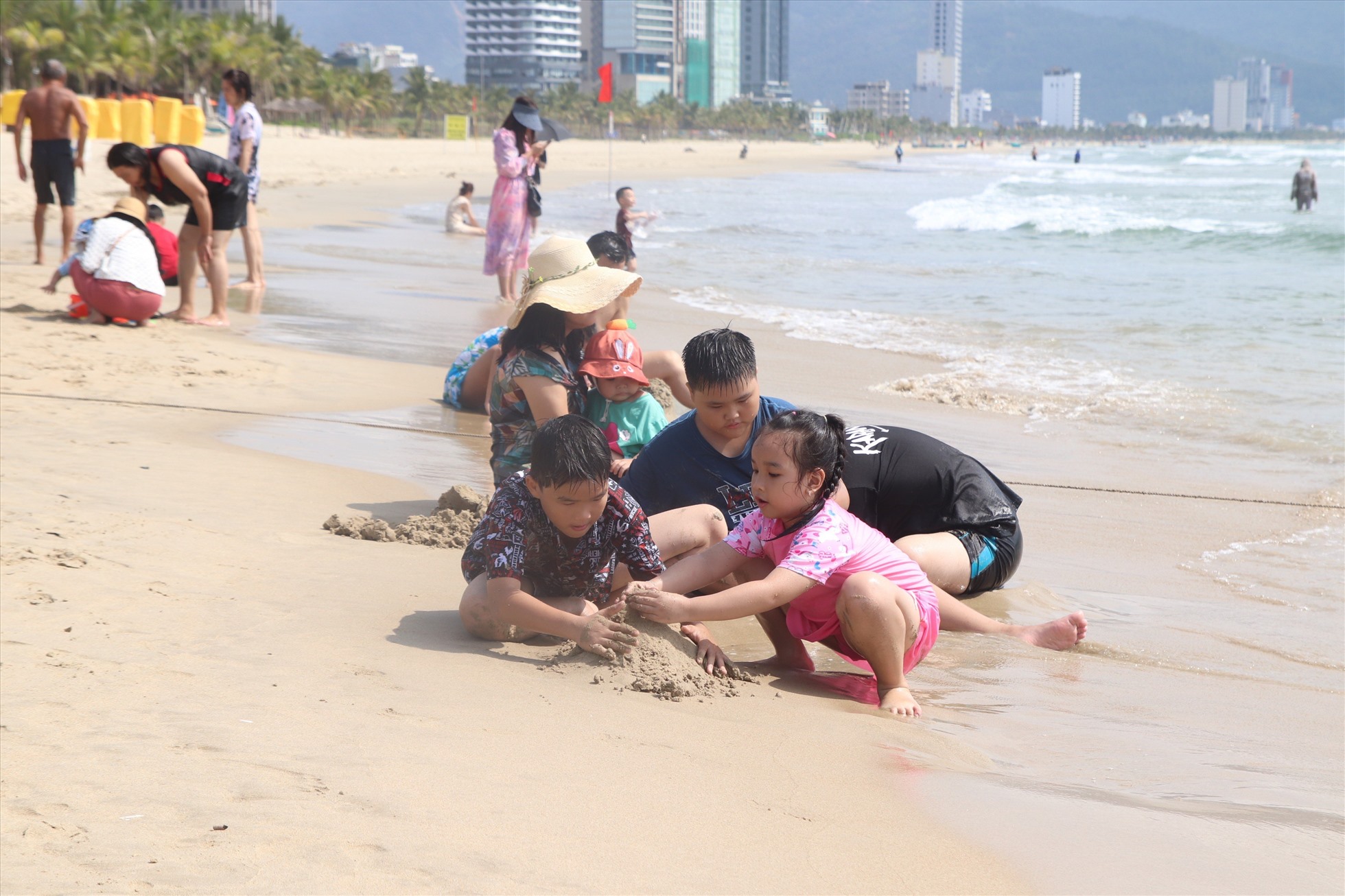 Trên bờ, nhiều khách du lịch nhỏ tuổi thích thú với việc đắp cát.