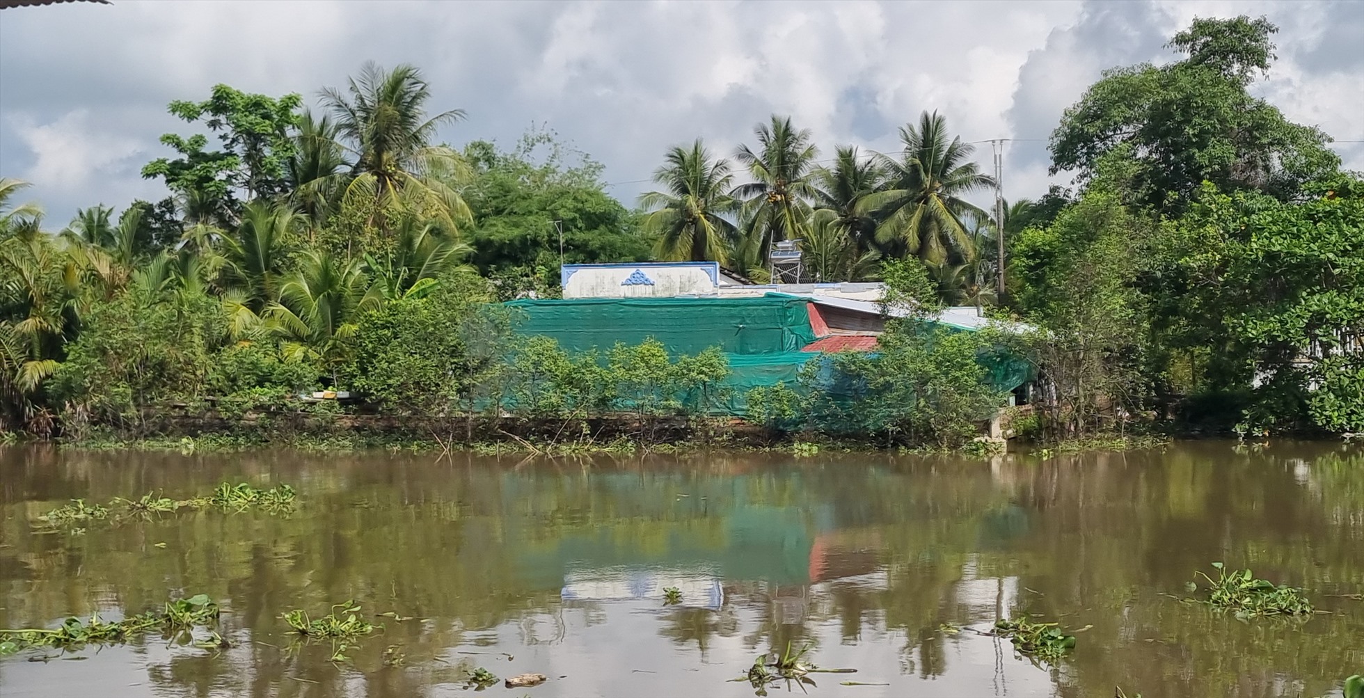Nhà ở cách 1 con sông lớn gần 100m vẫn phải che chắn bụi từ nhà máy xay xát lúc Phong Phú. Ảnh: Hoàng Lộc