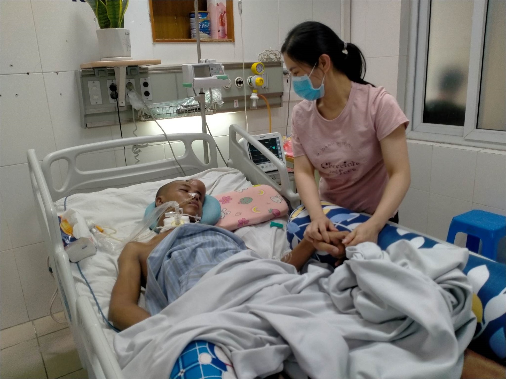 Chị Thanh nhìn chồng đau đớn nằm trên giường bệnh. Ảnh: Khánh Linh.