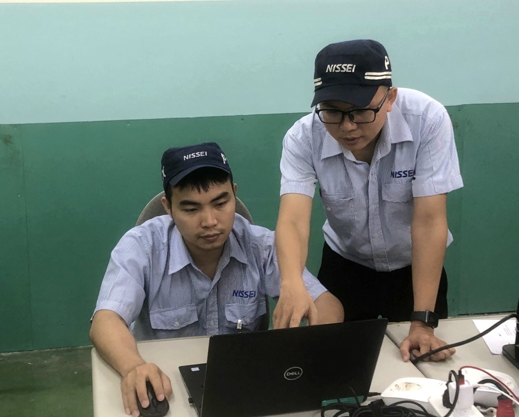Anh Nguyễn Văn Thuận - kĩ sư bảo trì của Công ty Nissei Electric Việt Nam (người đứng) - chỉ dẫn đồng nghiệp làm việc. Ảnh: Đức Long