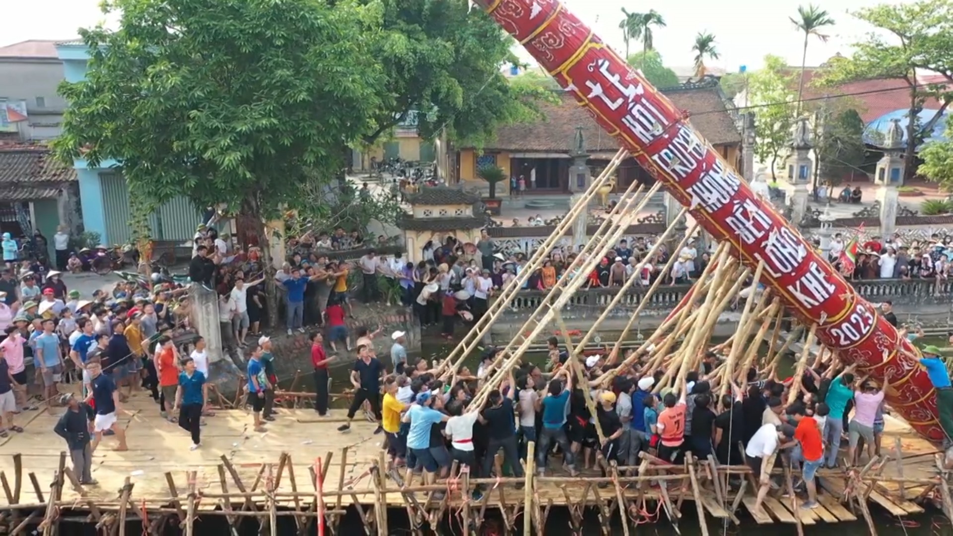 Thanh niên trai tráng khỏe mạnh trong làng cùng nhau tạo sức mạnh để dựng cây đình liệu đứng vững tại ao đền. Ảnh: Nam Hồng