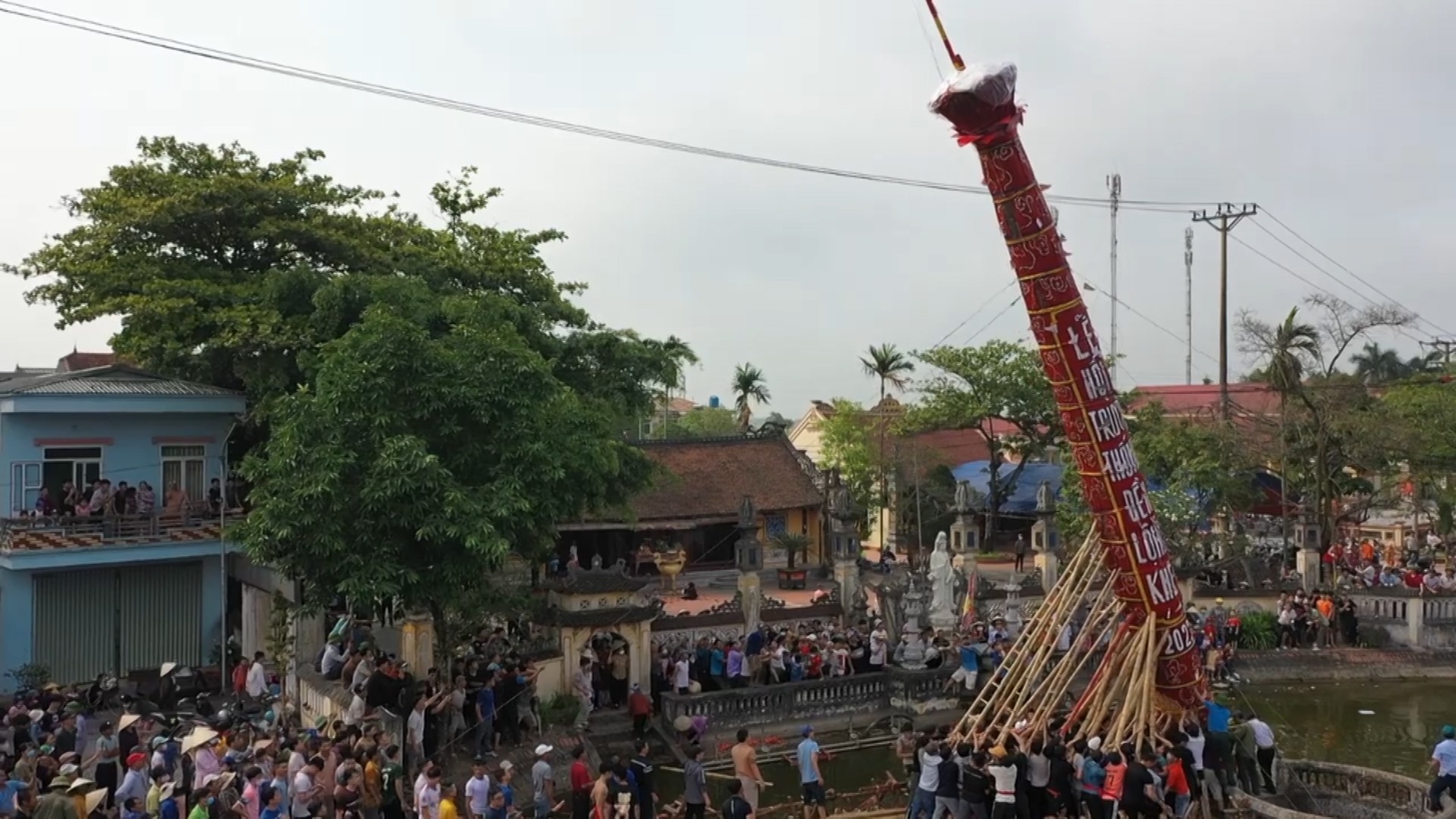 Thanh niên trai tráng khỏe mạnh trong làng cùng nhau tạo sức mạnh để dựng cây đình liệu đứng vững tại ao đền. Ảnh: Nam Hồng