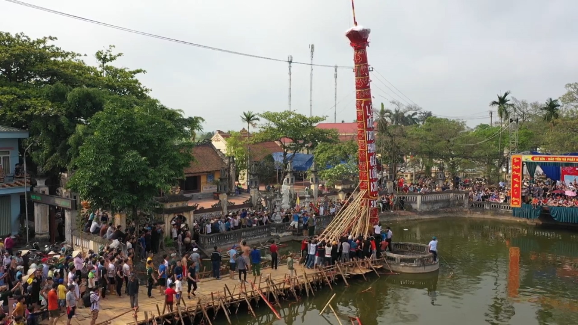 Thanh niên trai tráng khỏe mạnh trong làng cùng nhau tạo sức mạnh để dựng cây đình liệu đứng vững tại ao đền. Ảnh: Nam Hồng