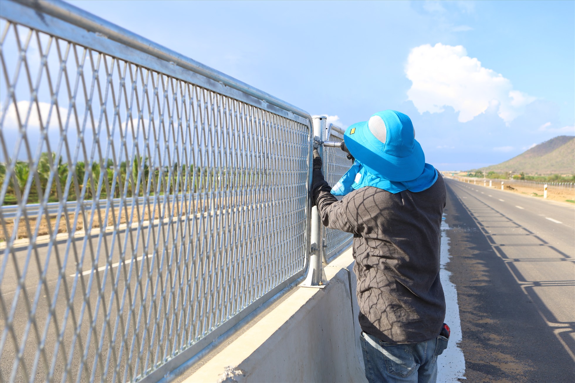 Trên công trình cao tốc Vĩnh Hảo - Phan Thiết, công nhân đang gia cố chặt ốc vít gắn các tấm lưới chống chói.