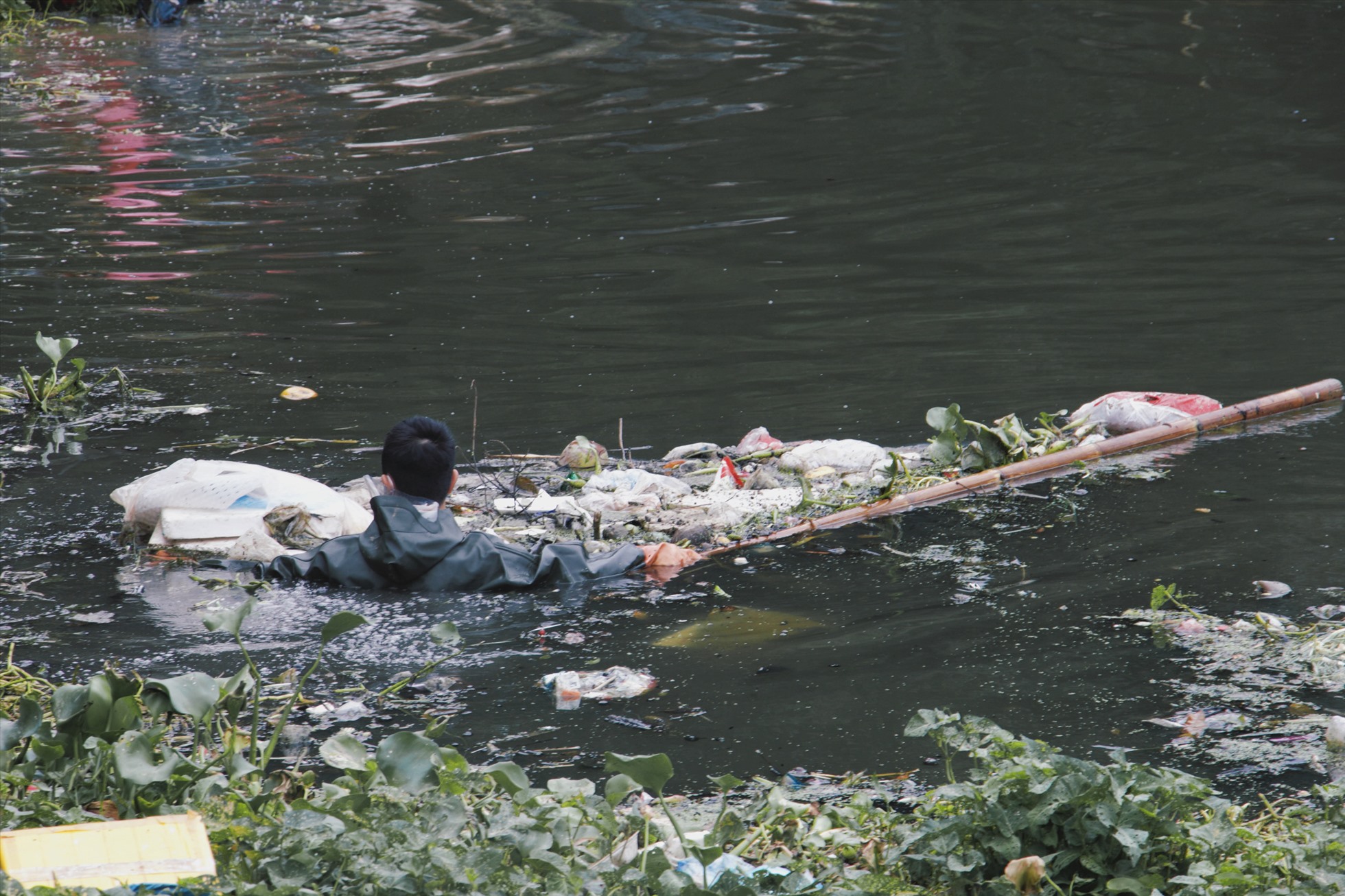 Các bạn trẻ trong nhóm Hà Nội Xanh tình nguyện lội mình xuống dòng nước bốc mùi, bất chấp rủi ro, nguy hiểm để nhặt rác, làm sạch dòng sông ô nhiễm. Ảnh: Hồng Ngọc