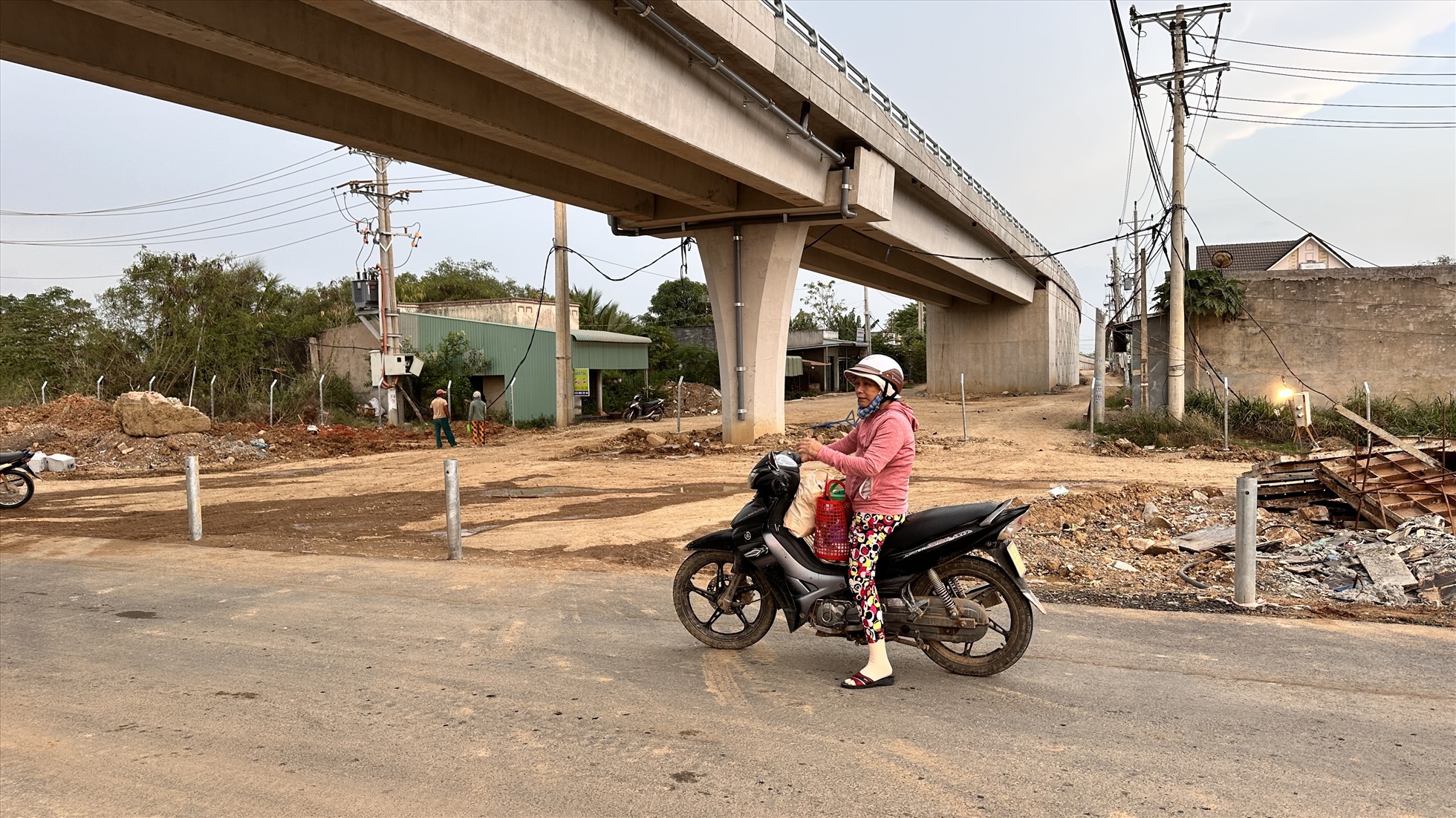 Một người dân bỡ ngỡ hỏi cách qua đường khi cao tốc đã đóng hộ lan một bên tại km229 qua xã Mương Mán, huyện Hàm Thuận Nam. Các công nhân đang thi công trên đường hướng dẫn cho người dân đi lên cầu vượt để qua đường.