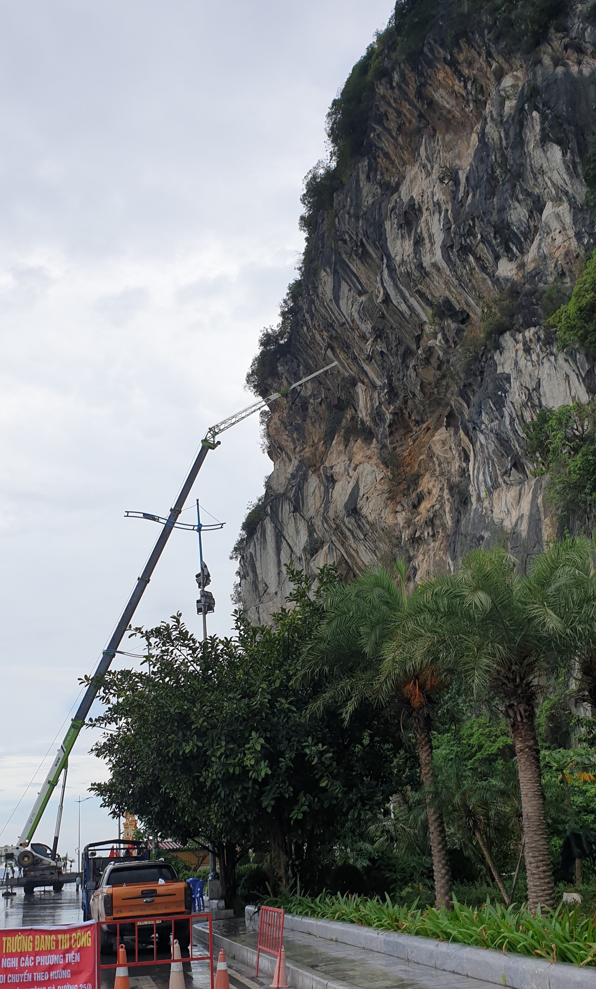 Sử dụng xe cẩu với cần cẩu dài để đưa công nhân lên lưng chừng núi để xử lý điểm có nguy cơ sạt lở. Ảnh: Nguyễn Hùng