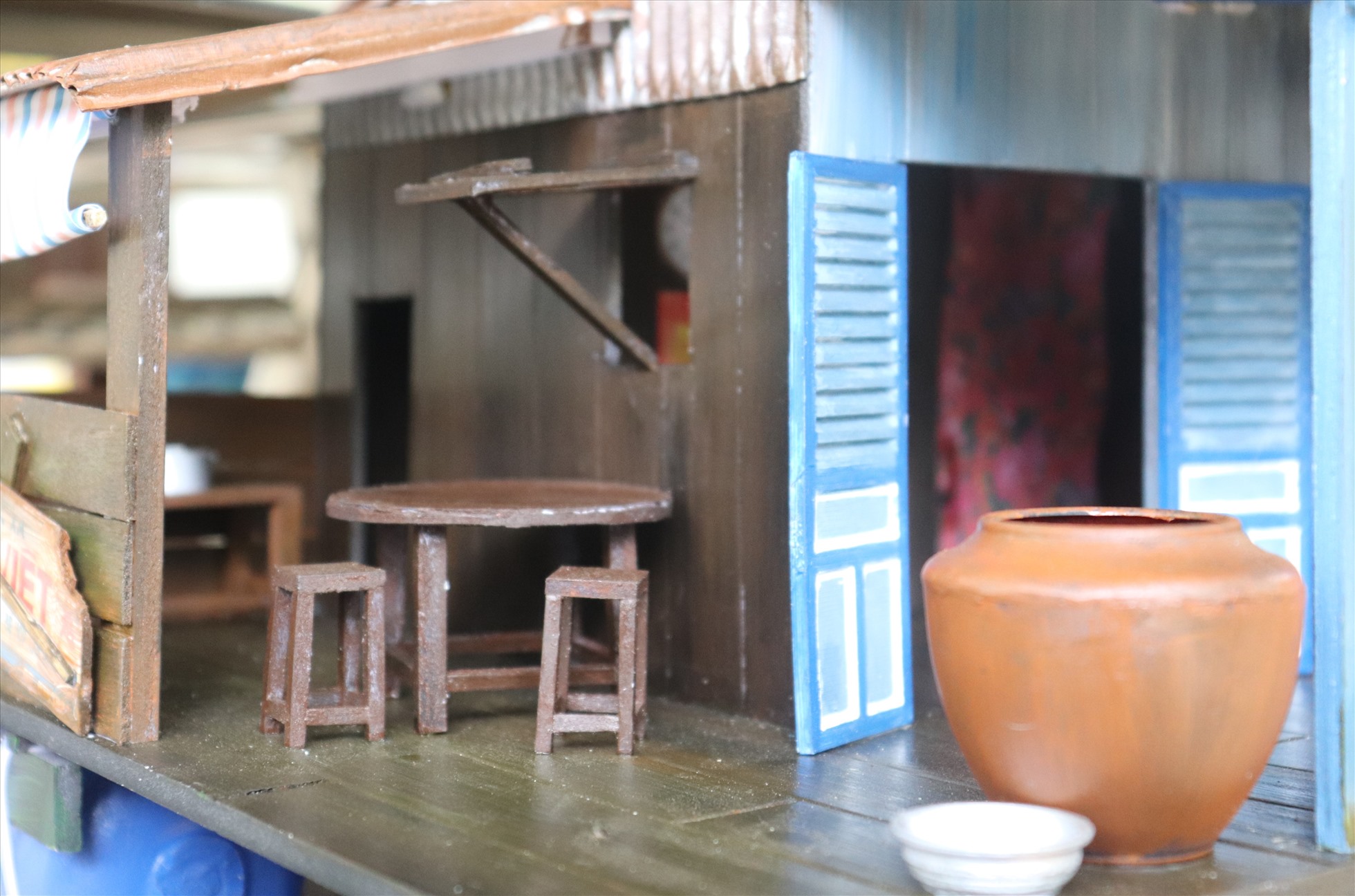 Lu chứa nước, bộ bàn ghế gỗ kê ở một gốc ngôi nhà được Tùng làm y như thật.