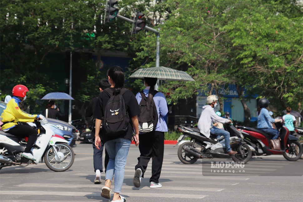Nhiều người chạy xe máy vội vã trên đường để tránh nắng.