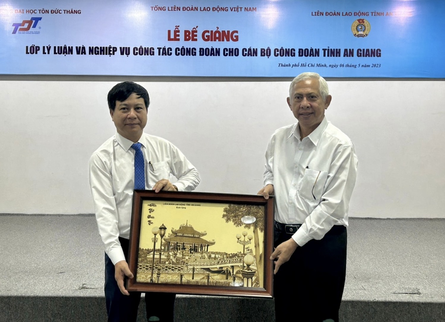 Chủ tịch Liên đoàn Lao động tỉnh An Giang Nguyễn Thiện Phú (phải) trao quà lưu niệm cho Trường Đại học Tôn Đức Thắng. Ảnh: Cẩm Tú