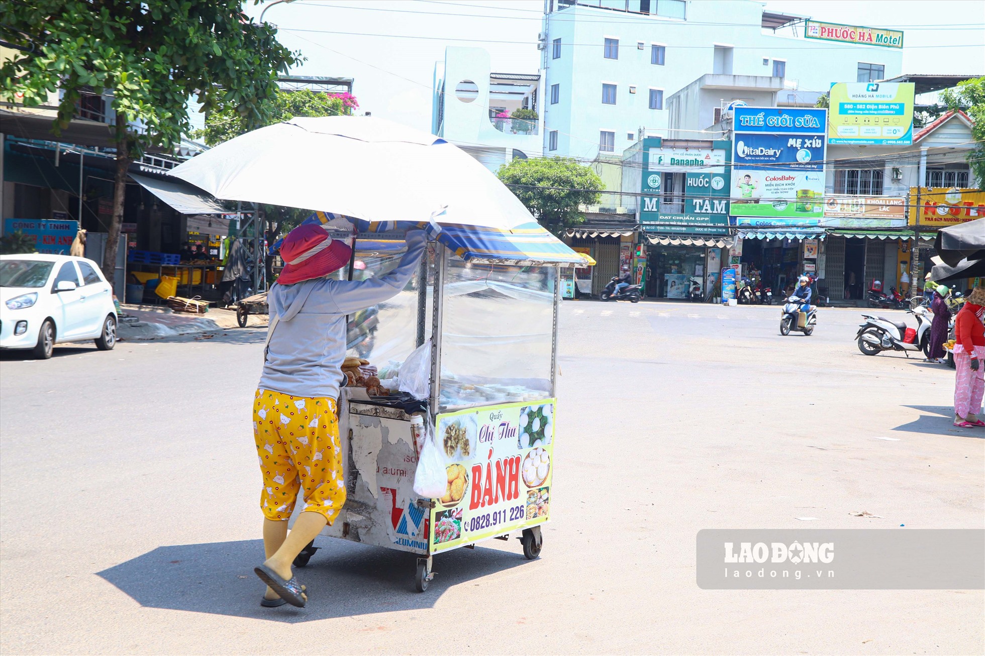 Với nền nhiệt độ ngoài trời cao, người bán hàng rong đã phải lắp ô che nắng khi di chuyển trên đường.