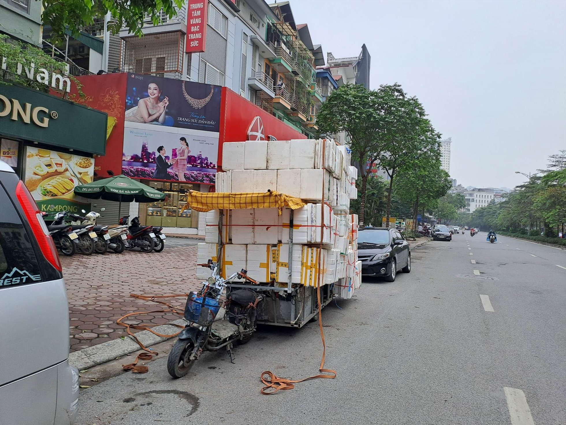 Xe máy chế kéo theo hàng hóa cồng kềnh phía sau. Ảnh: Chụp tại đường Nguyễn Hoàng, Hà Nội