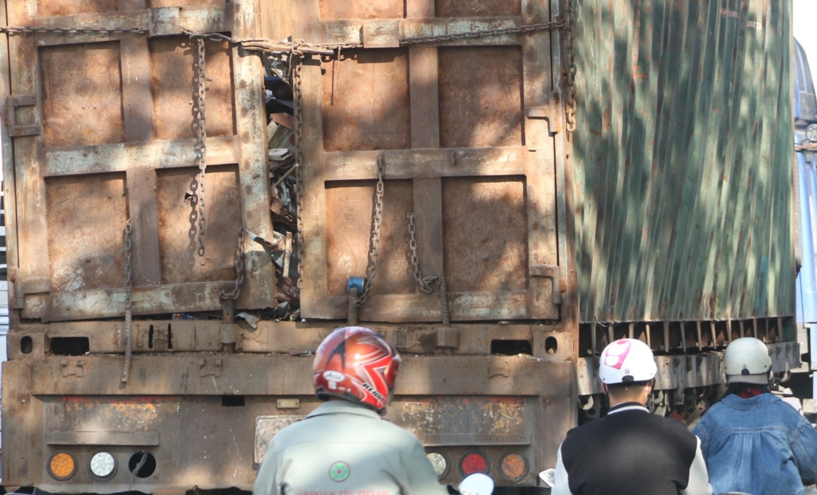 Các thùng container cũ méo chở sắt vụ hở ra ngoài rất dễ rơi xuống đường gây nguy hiểm cho người đi xe máy. Ảnh: Dương Bình