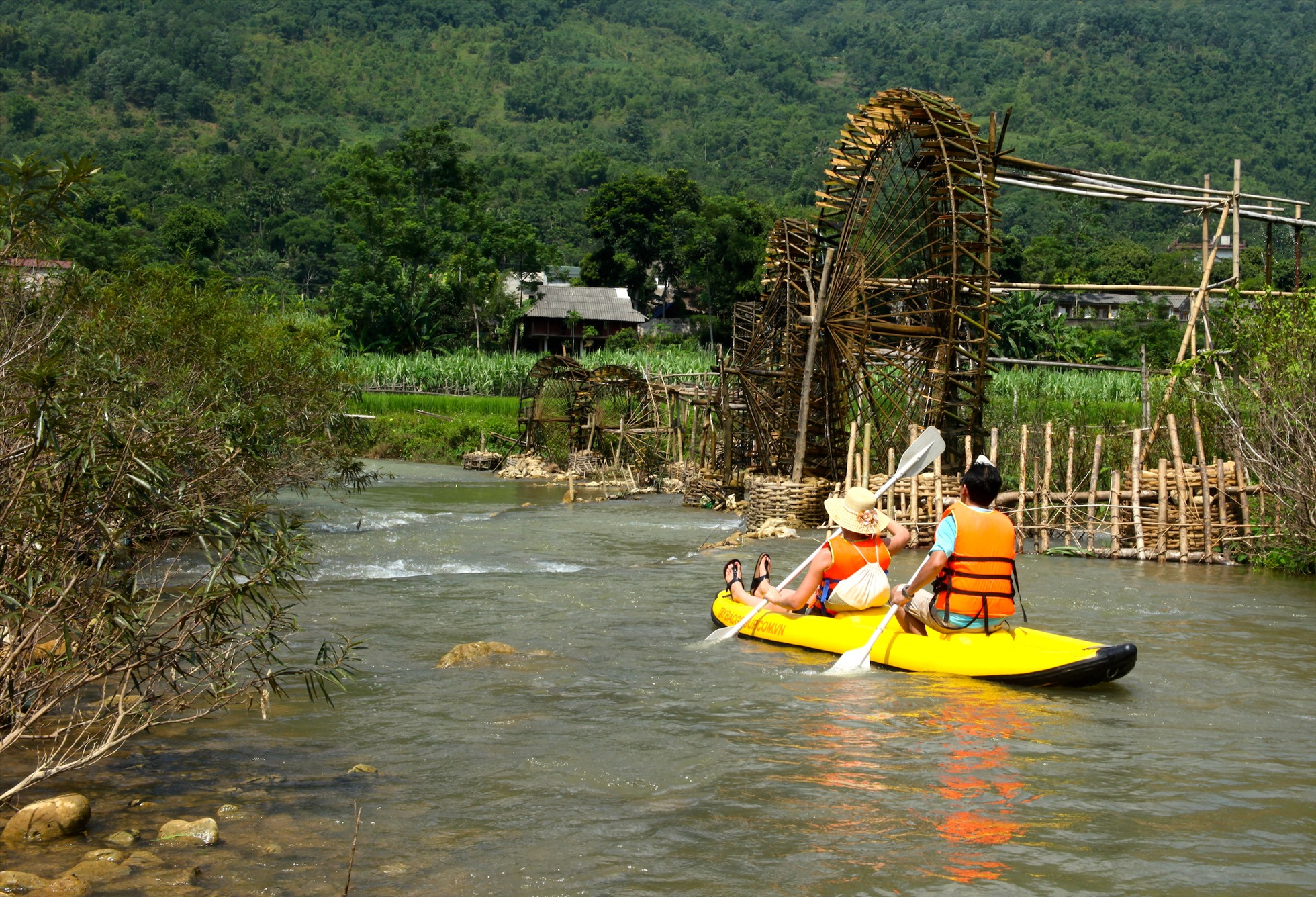 Khách du lịch chèo kayak trên suối Chàm, phía xa là những cọn nước của người Thái. Ảnh: Pù Luông Retreat
