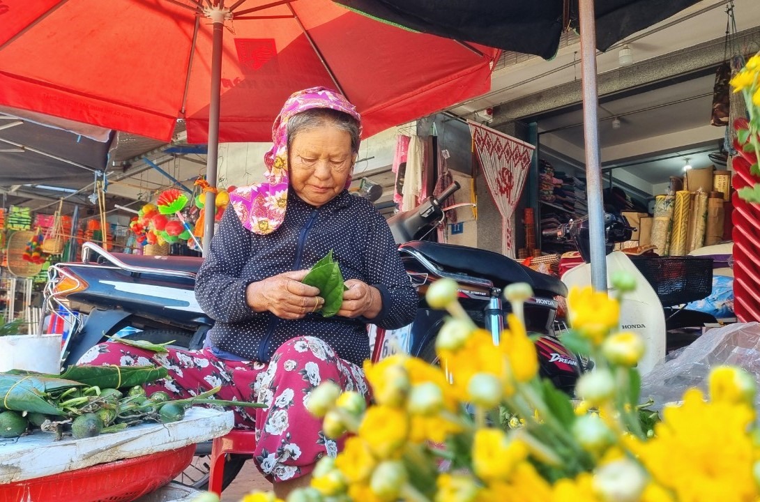 Cụ bà Trần Thị Hiệp (68 tuổi) thản nhiên tem trầu giữa phố. Cứ mỗi dịp mồng 5.5 cụ lại gánh hàng trầu cau ra chợ bán để tìm niềm vui tuổi già. Ảnh Hoàng Bin