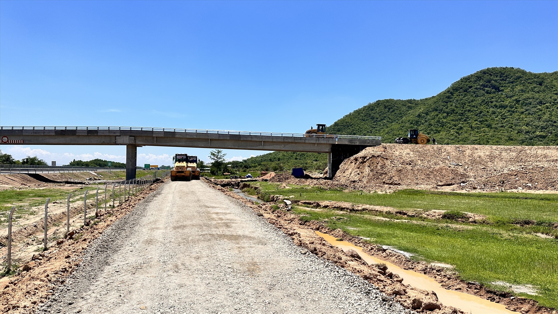 Nhân công, xe lu tập trung thi công tại khu vực cầu vượt núi Xả Thô, xã Hàm Trí, huyện Hàm Thuận Bắc.