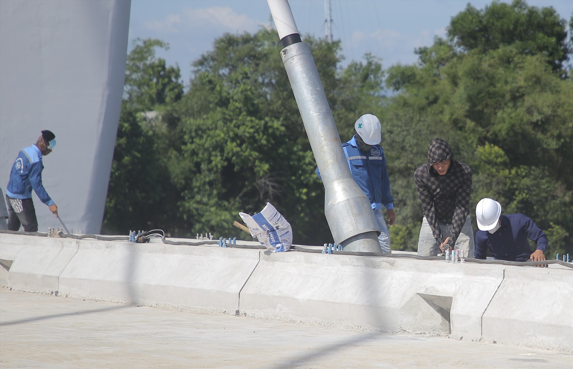 Công nhân đang dọn vệ sinh trên mặt cầu để chuẩn bị thảm lớp nhựa, hoàn tất mặt đường trên cầu.