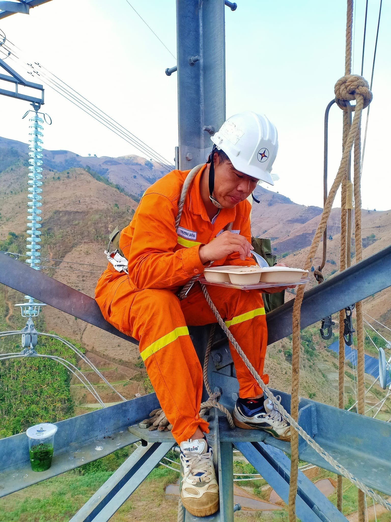 Bữa ăn vội ngay trên cột điện giữa tiết trời nắng nóng. Ảnh: Hồng Thiệu