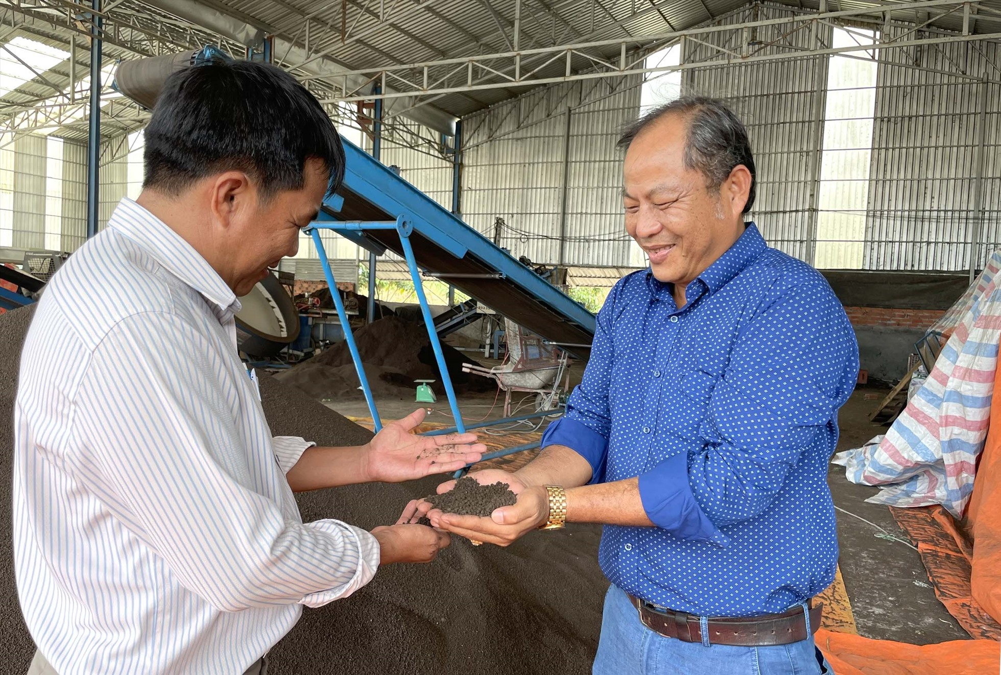 Anh Chào (phải) chia sẻ sản phẩm phân trùn quế với anh Hồ Văn Lý, Phó trưởng Phòng NNPTNT huyện Tân Hồng. Ảnh: Mỹ Lý