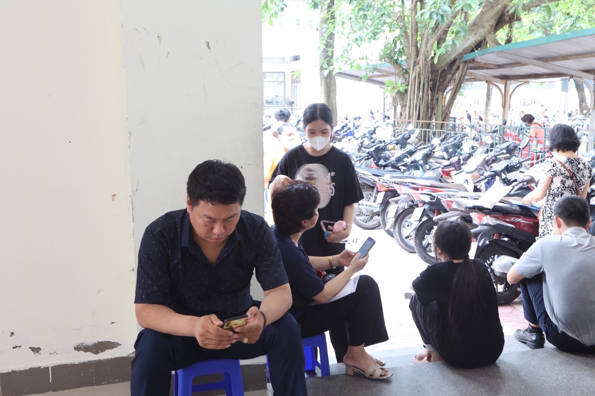 Phụ huynh vật vờ xếp hàng xuyên đêm tại cổng Trường THCS&THPT Tạ Quang Bửu để đăng kí tuyển sinh lớp 10. Ảnh: Trà My