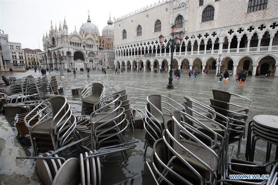 Mọi người đi bộ qua Quảng trường San Marco bị ngập nước ở Venice, Italy, ngày 13.11.2019. Ảnh: Xinhua