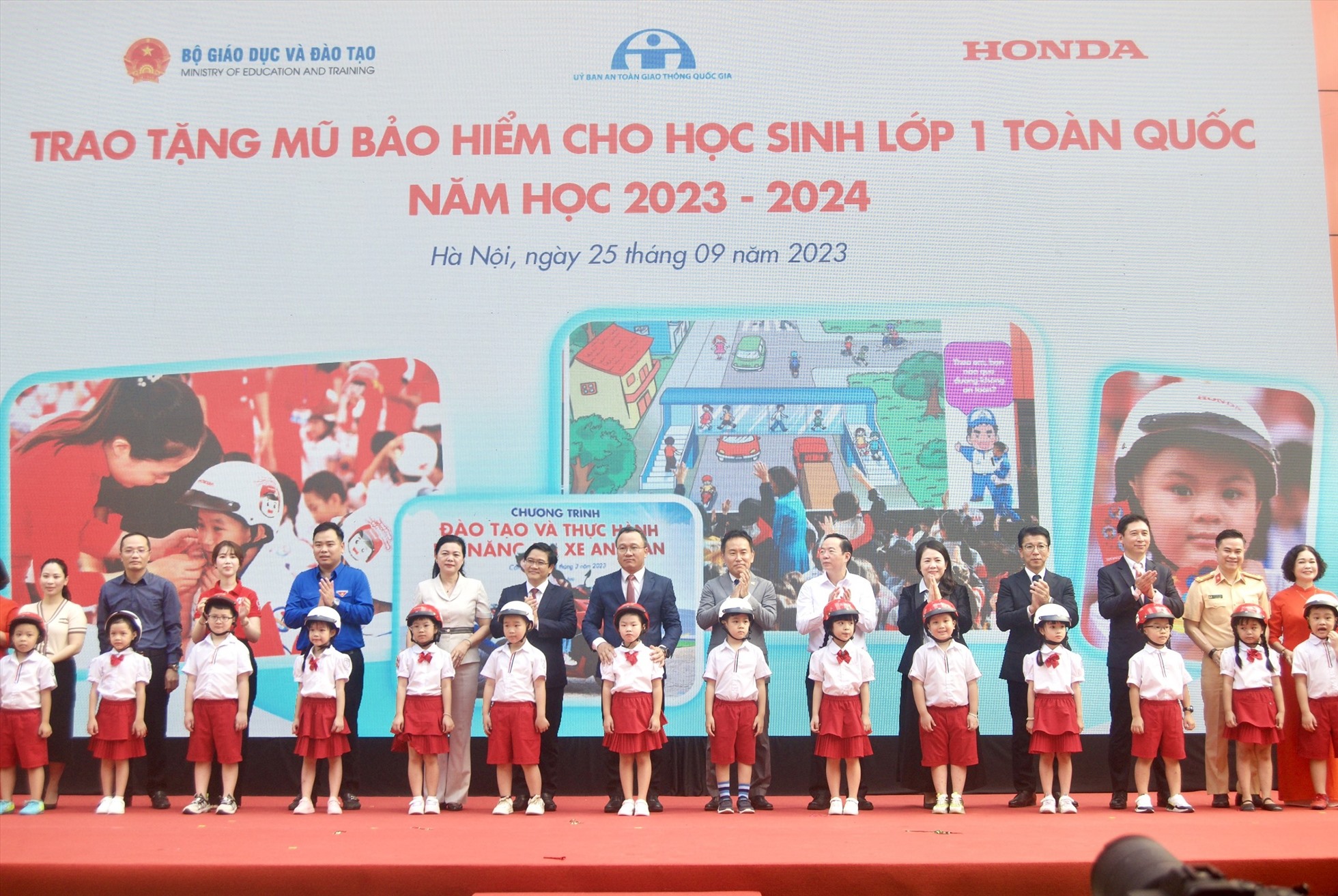 Các đại biểu trao tặng mũ bảo hiểm cho các em học sinh lớp Một trường Tiểu học Phú Đô. Ảnh: Vân Trang