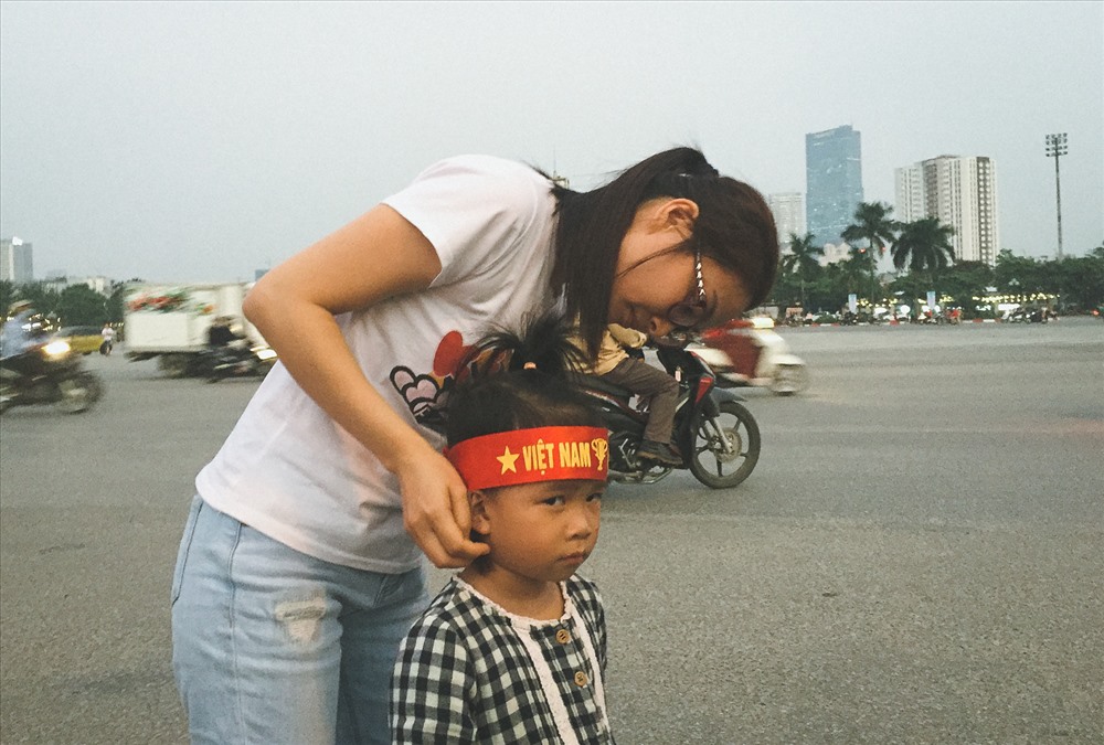 Một CĐV nhí được mẹ đeo chiếc băng đầu cổ vũ ĐTVN.