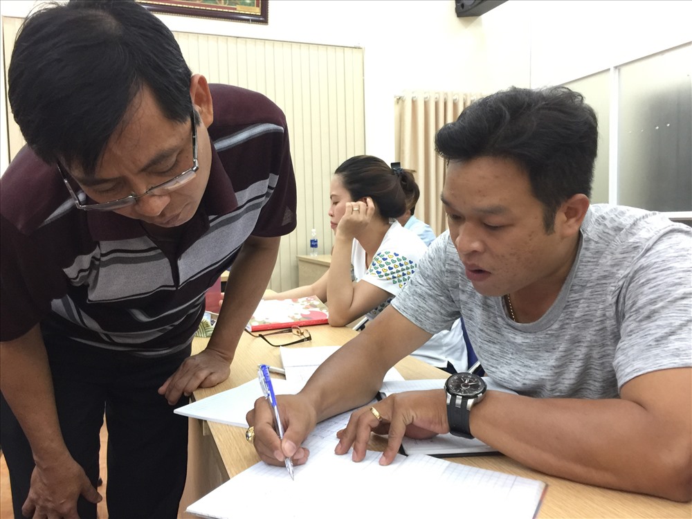 Anh Nguyễn Anh Vũ (trái ảnh) và anh Đào Long Bình trao đổi bài vở trước khi vào giờ học - Ảnh: L.T