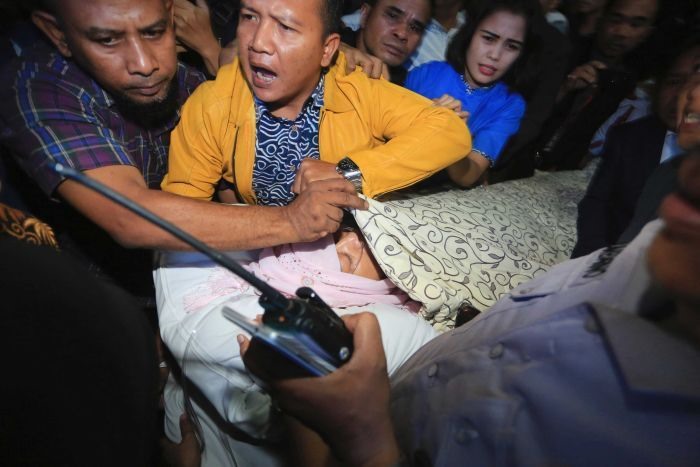 Các trợ lý dùng chăn để che chắn cho Chủ tịch Quốc hội Indonesia Setya Novanto khi ông nằm trên cáng để chuyển đến bệnh viện ở Jakarta. Ảnh: AP