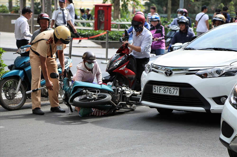 Cảnh sát giao thông giúp một phụ nữ bị ngã xe gần trung tâm thương mại. Ảnh: Trường Sơn