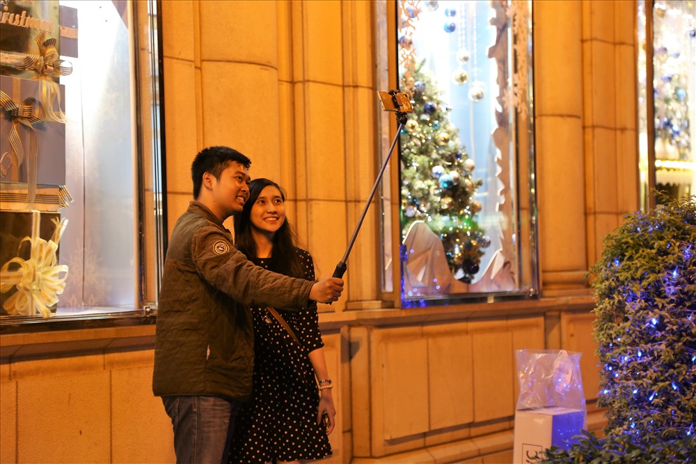 Đôi bạn trẻ trang thủ chụp hình lưu niệm trước một tòa nhà được trang trí rực rỡ dịp Giáng sinh. Ảnh: Trường Sơn