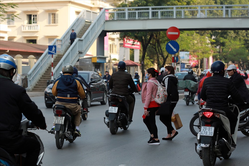 Người đi bộ băng qua đường tại cổng Học viện Ngân hàng, phố Chùa Bộc (Hà Nội). Ảnh: HẢI NGUYỄN