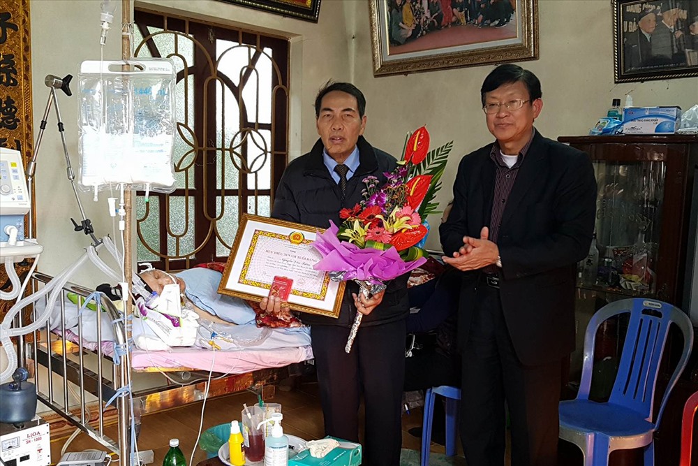 Bí thư Huyện ủy Vĩnh Bảo (phải) trao huy hiệu 70 năm tuổi Đảng cho gia đình cụ Nguyễn Văn Tươm.