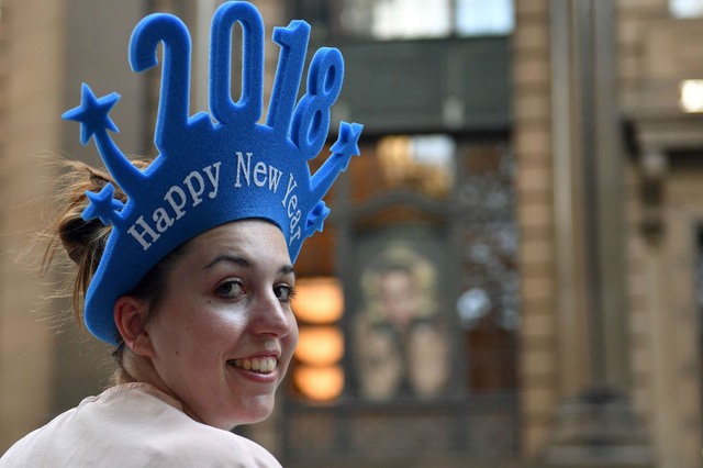 Một phụ nữ đội mũ có dòng chữ “Chúc mừng năm mới 2018” tại thành phố Sydney, Australia để chuẩn bị chào đón năm mới. (Ảnh: AFP)