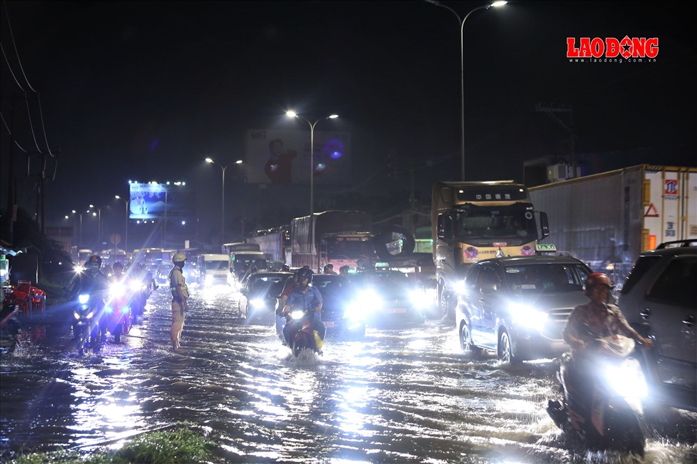 Khoảng gần 20h đêm 6.12, triều cường bắt đầu dâng lên khiến giao lộ QL1 và đường Nguyễn Hữu Trí bắt đầu bị ngập sâu, dòng xe qua đây bị ùn ứ, xe máy phải leo lên lề để di chuyển. Ảnh: Trường Sơn