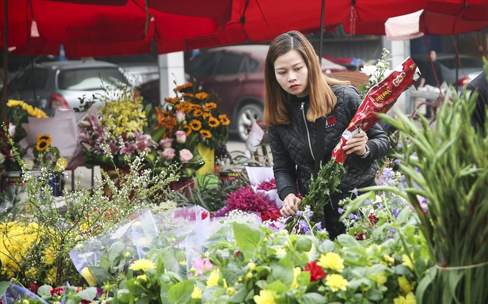 Người phụ nữ đang ngắm những bông hoa đẹp nhất mua về thắp hương gia tiên.
