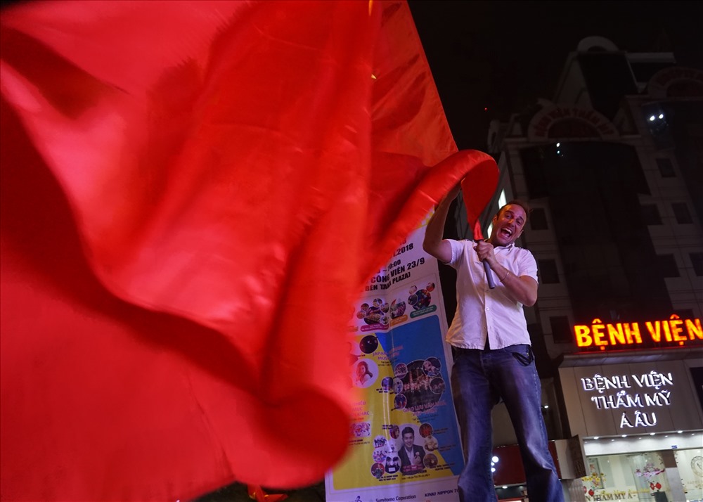 Một người đàn ông nước ngoài phấn khích lên lên hộp tủ điện và cầm lá cờ Việt Nam “khủng” vẫy mừng.