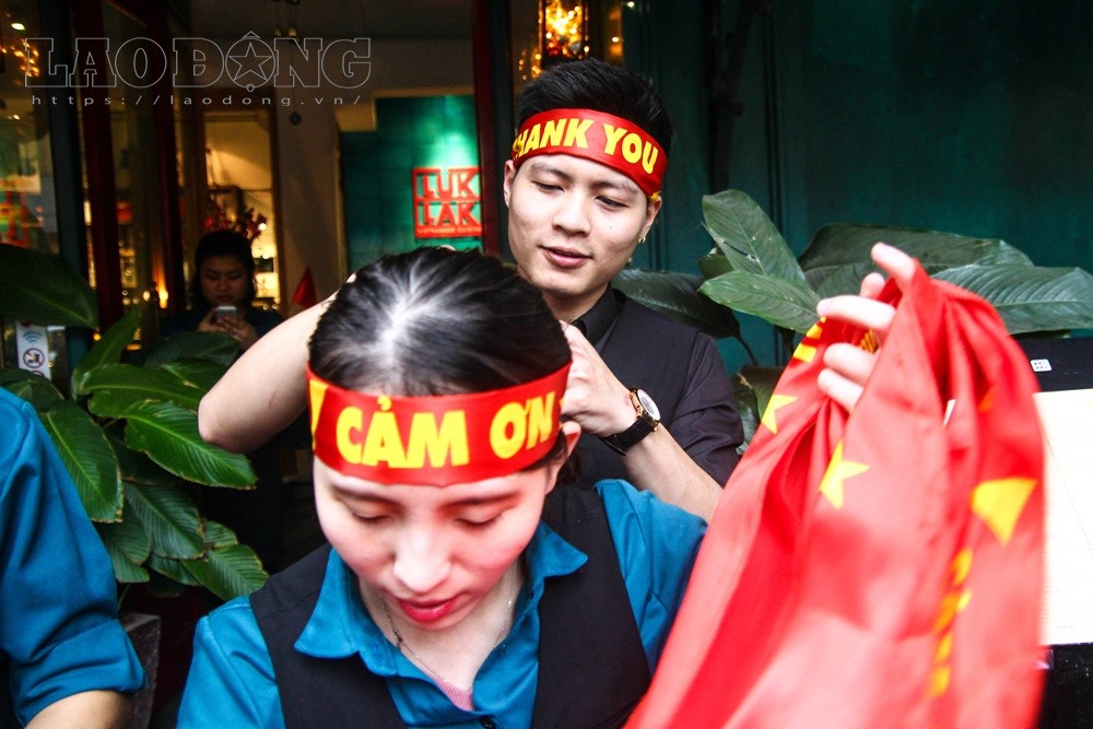 Tại Hà Nội, một quán cafe đã tặng hàng trăm bộ hình hiệu, khẩu hiệu cờ đỏ sao vàng cho các CĐV cùng chung niềm đam mê bóng đá.