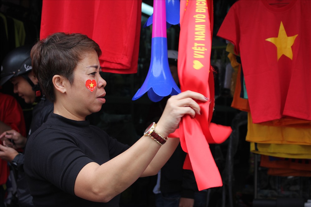 Nhiều mặt hàng cỗ vũ cho tuyển Việt Nam như băn rôn đeo đầu, lá cờ, áo lá cờ, lá cờ dán mặt, còi, kèn đều được bày bán với số lượng nhiều. Ảnh: Xuân Hậu