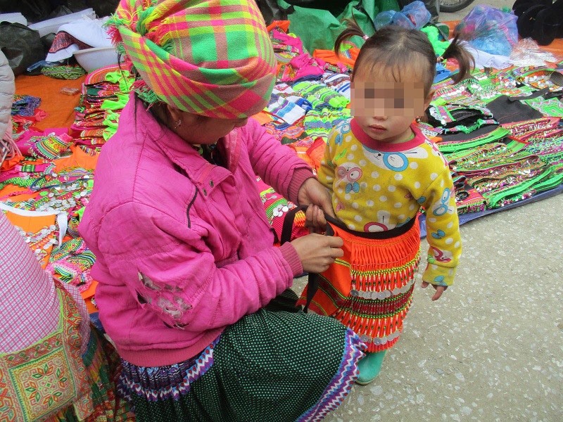 Người mẹ H'Mông mua váy diện tết cho con dù chị vẫn đang phải mặc áo rách. Ảnh: PV