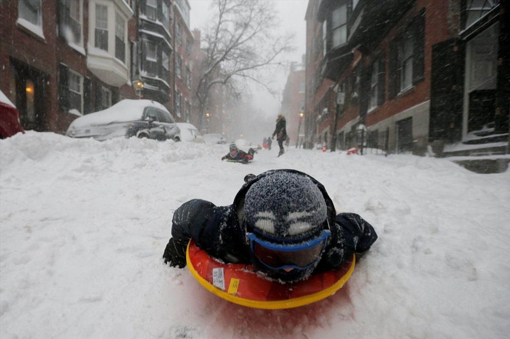 Một cậu bé trượt trên mặt đường Beacon Hill trong cơn bão Grayson ở Boston. Ảnh: Reuters. 