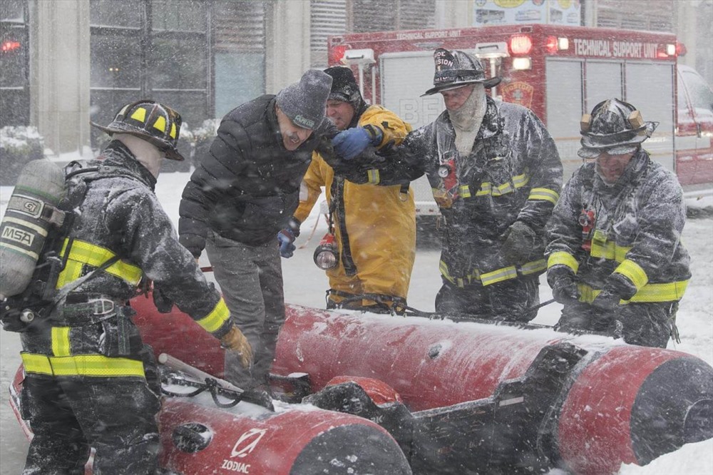Lính cứu hỏa đang giúp đỡ một người đàn ông trong cơn bão tuyết ở Boston. Ảnh: EPA